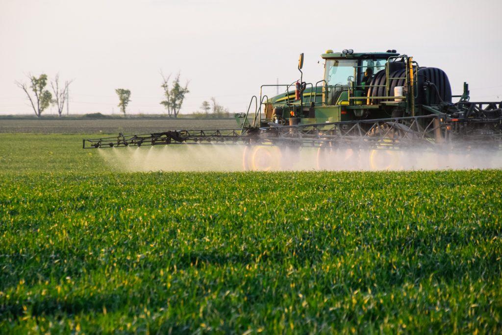 Tractor being used to spray herbicides onto crops to combat weeds and other infestations